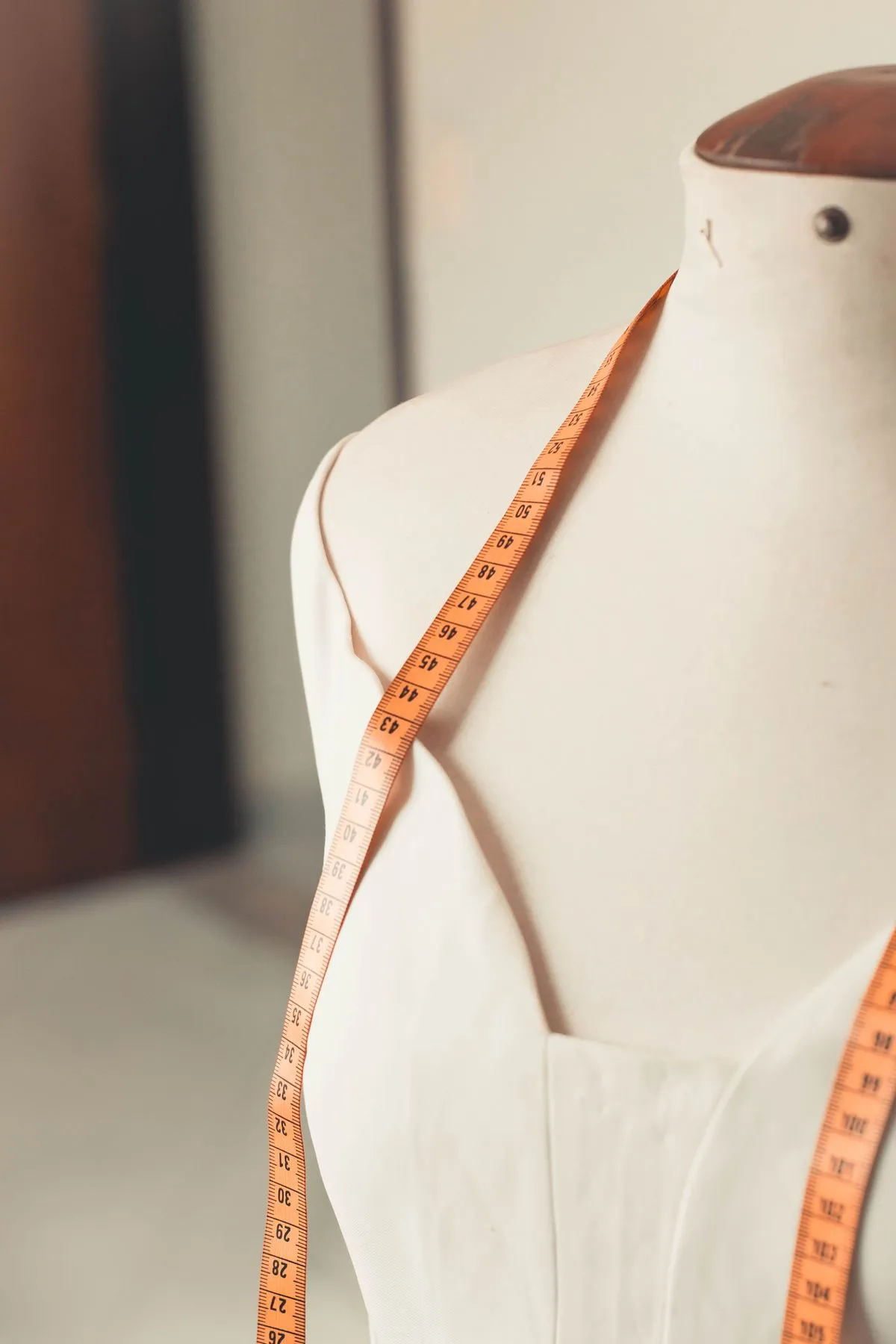 A dressmaker's form with a tape measure draped over it