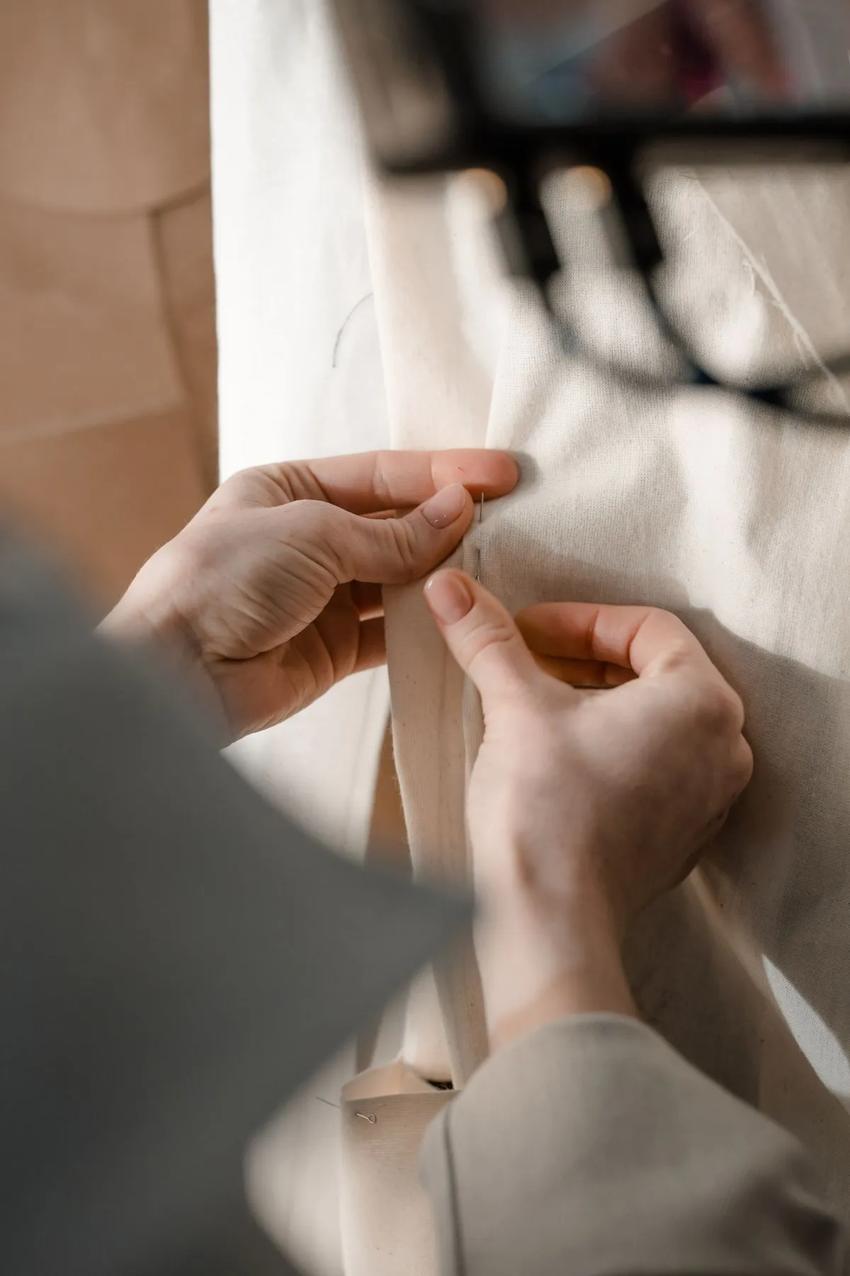 Hands pinning a seam on a garment during a fitting